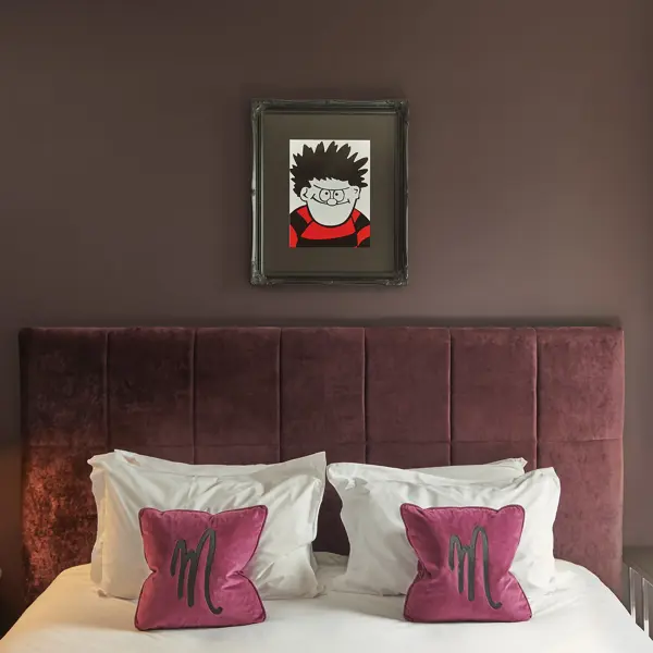 An elegantly made bed adorned with two plump pillows and a tastefully framed picture hanging on the wall.