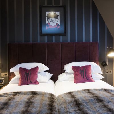 Two beds placed side by side with red velvet headboards.