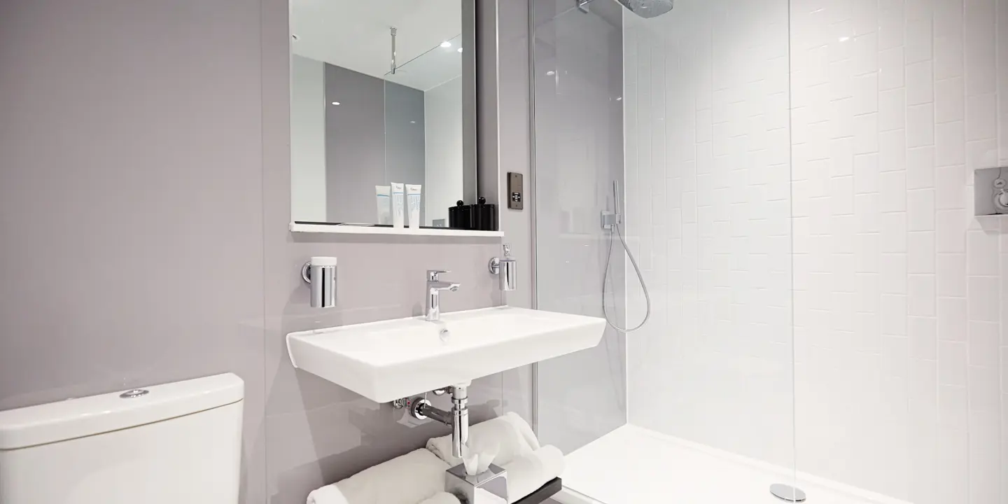 All white bathroom featuring a toilet, sink and shower.