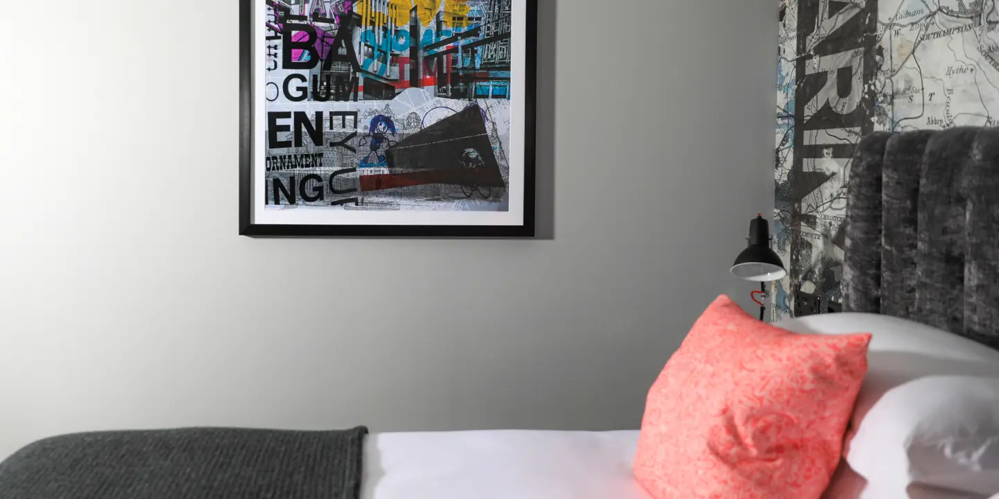 Bedroom featuring a white bed and an art piece adorning the wall.