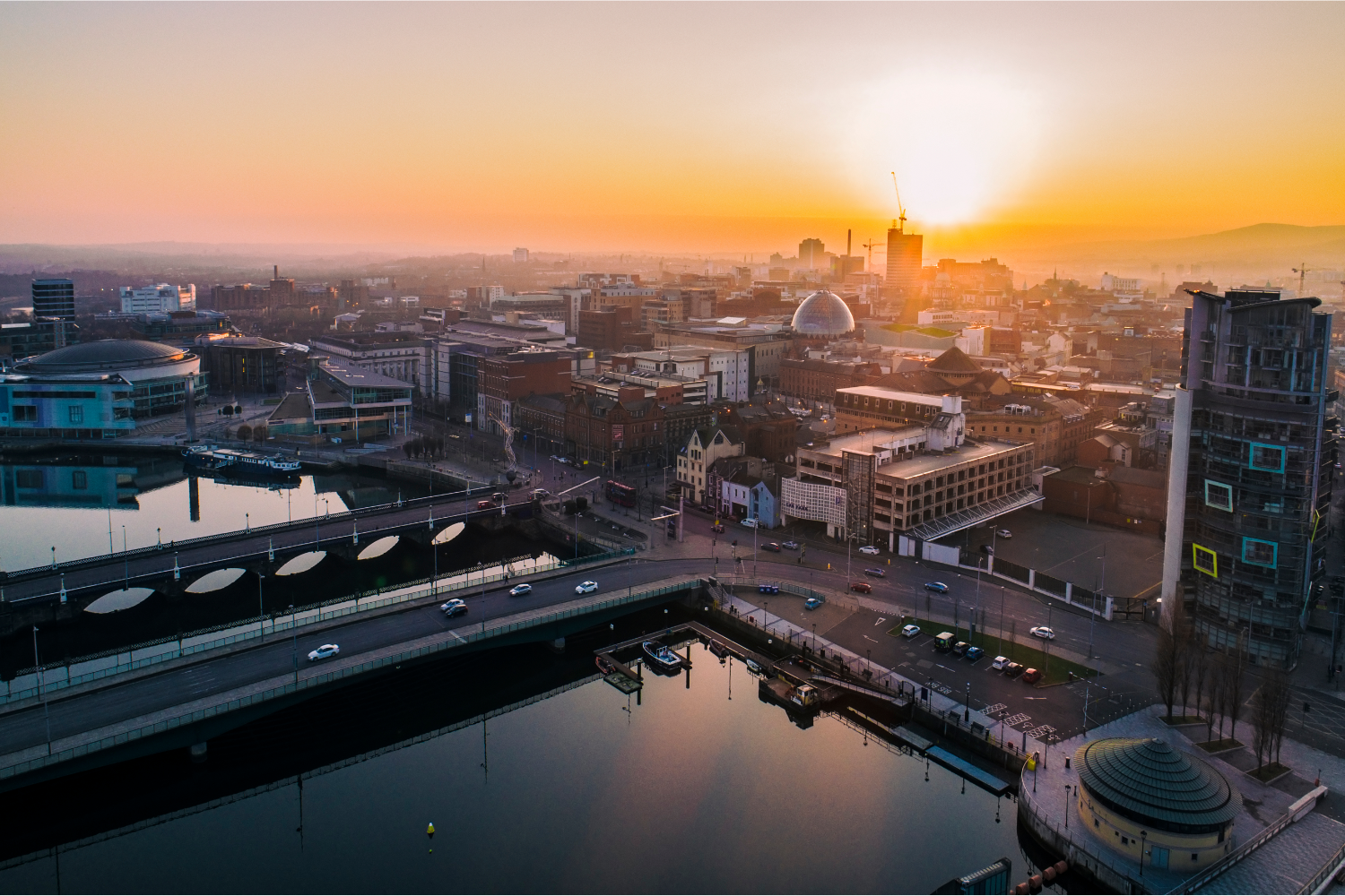 Sunset over a city skyline with boats in the water.