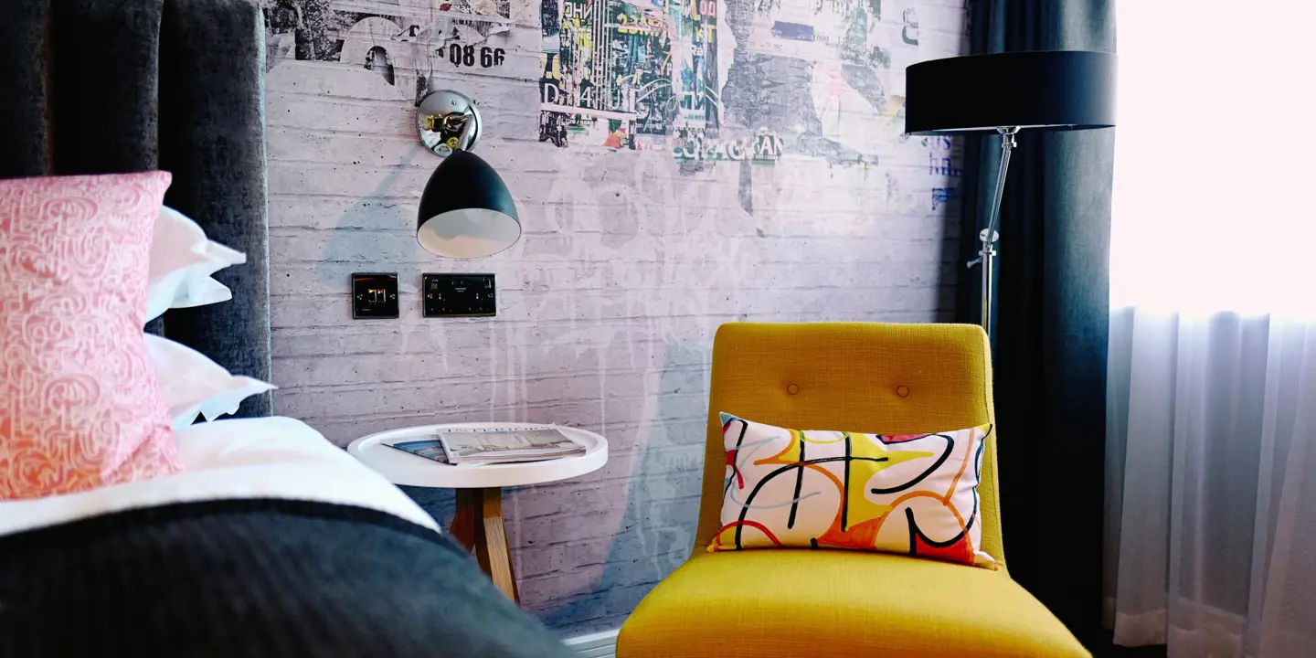 Yellow chair positioned in a bedroom adjacent to a window.