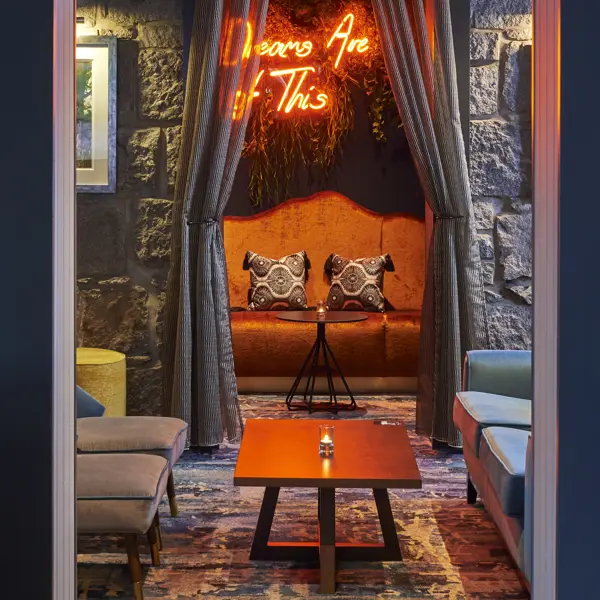 A well-furnished and cosy bar lounge adorned with a vibrant neon sign.
