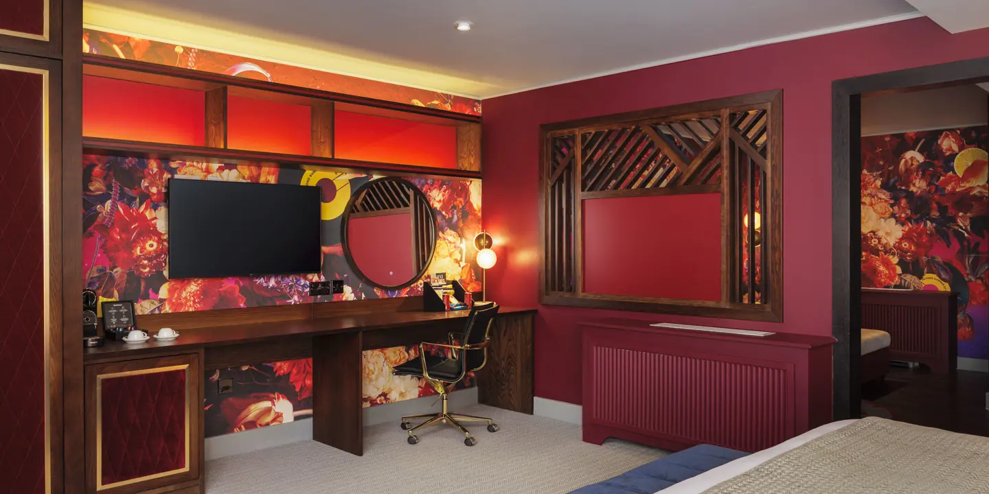 A spacious room featuring a comfortable bed, ottomon, and desk.