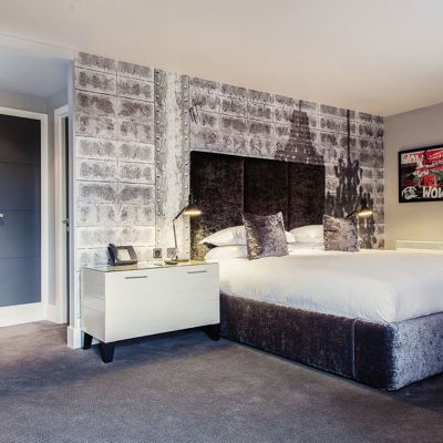 Bedroom featuring a grey velvet bed with white bedside tables.