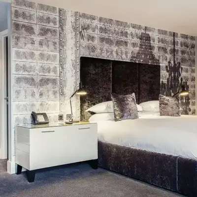 Bedroom featuring a grey velvet bed with white bedside tables.