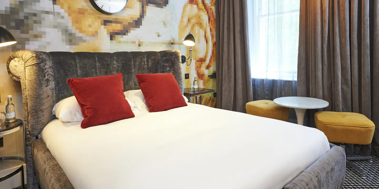 Hotel room featuring a comfortable bed and a wall-mounted clock.