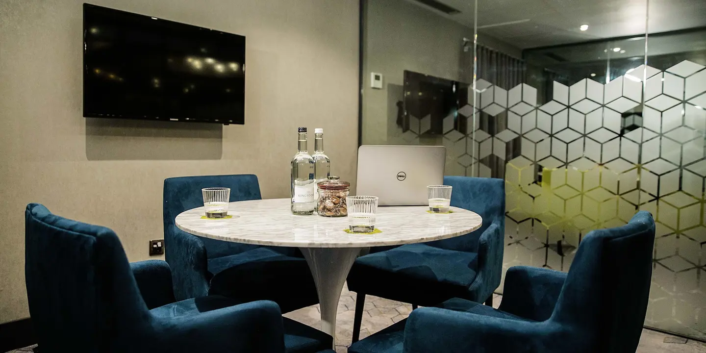 A well-furnished meeting room featuring a table, chairs, and a television.