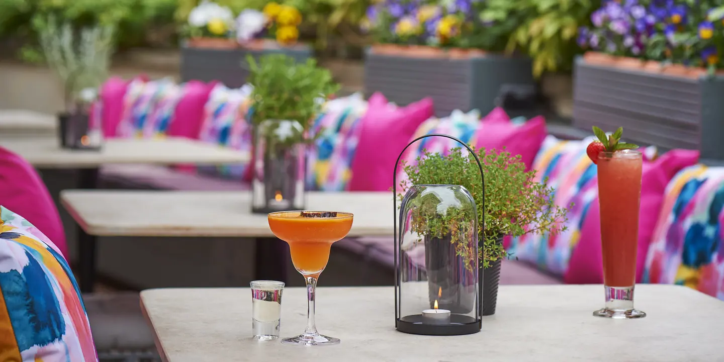 A table featuring two glasses of wine and a vase filled with flowers.