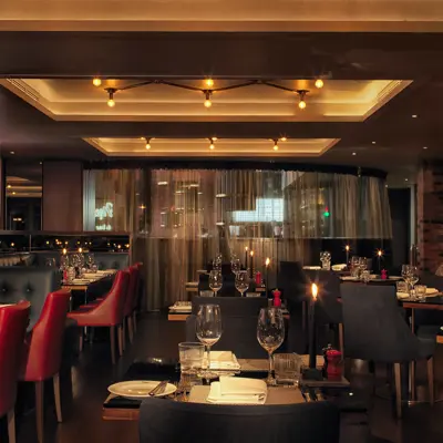 A candle lit dining hall with a mixture of black and red decor