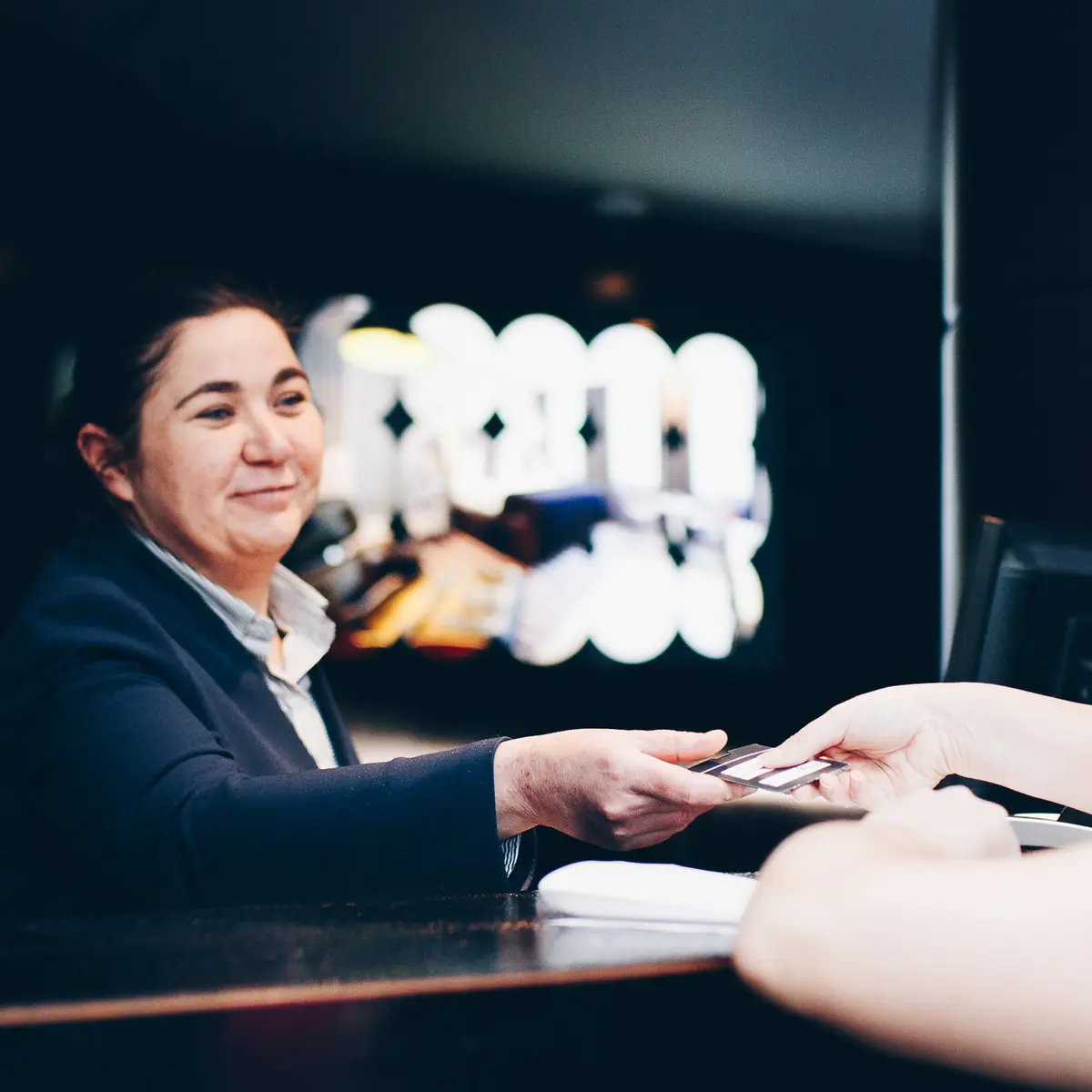 Receptionist handing hotel key card to guest
