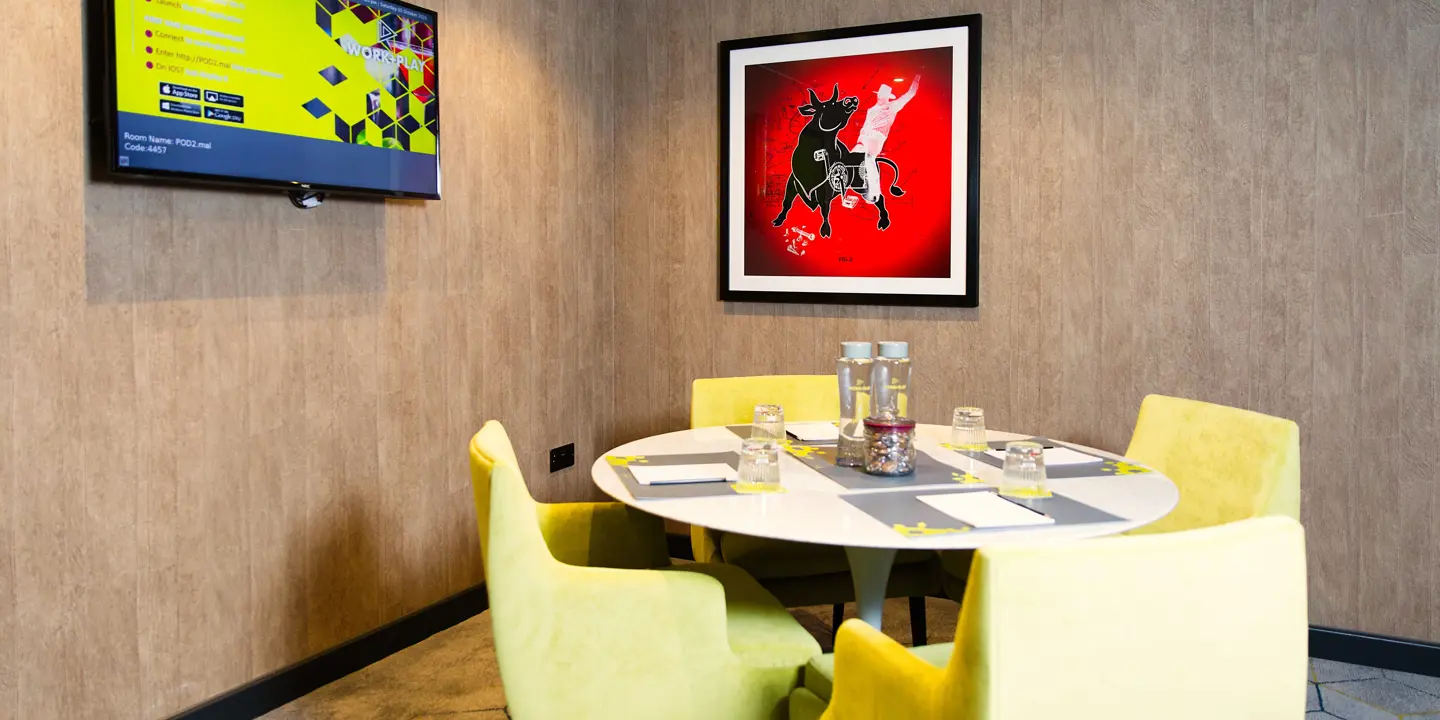 Table with yellow chairs and a flat-screen TV.