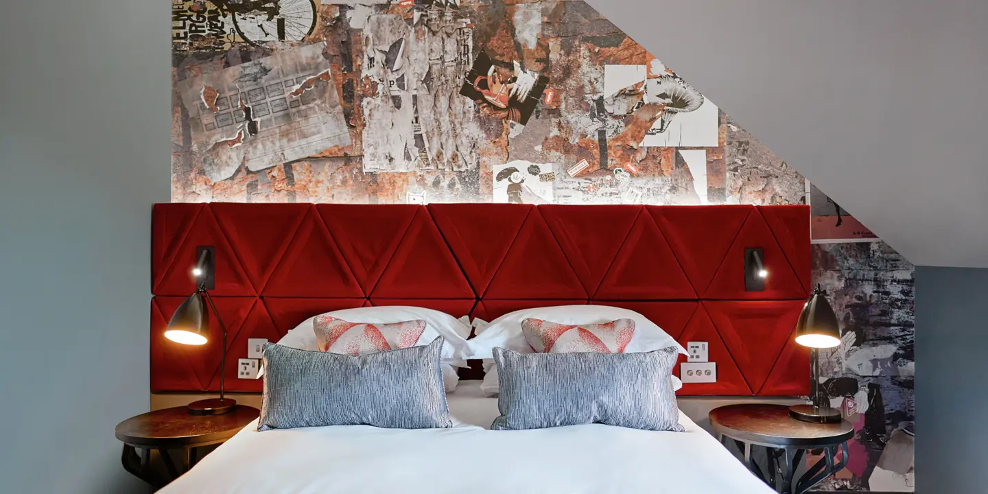 A bed featuring a vibrant red headboard and matching pillows.