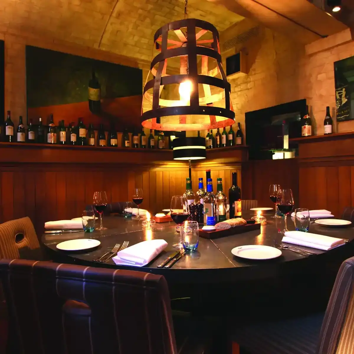 A dining room featuring a table, chairs, and bottles of wine.