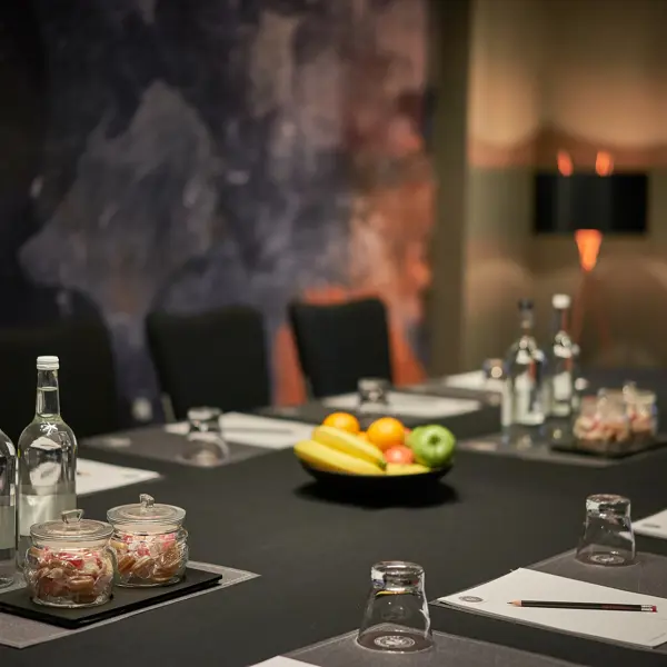 A table displaying a bowl of fresh fruit and bottles of water.