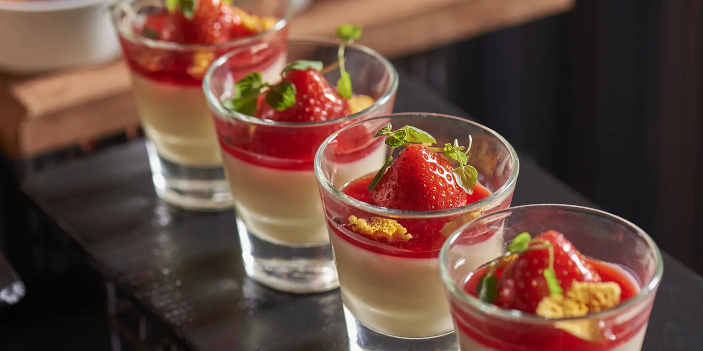 Table with four dessert-filled glasses.