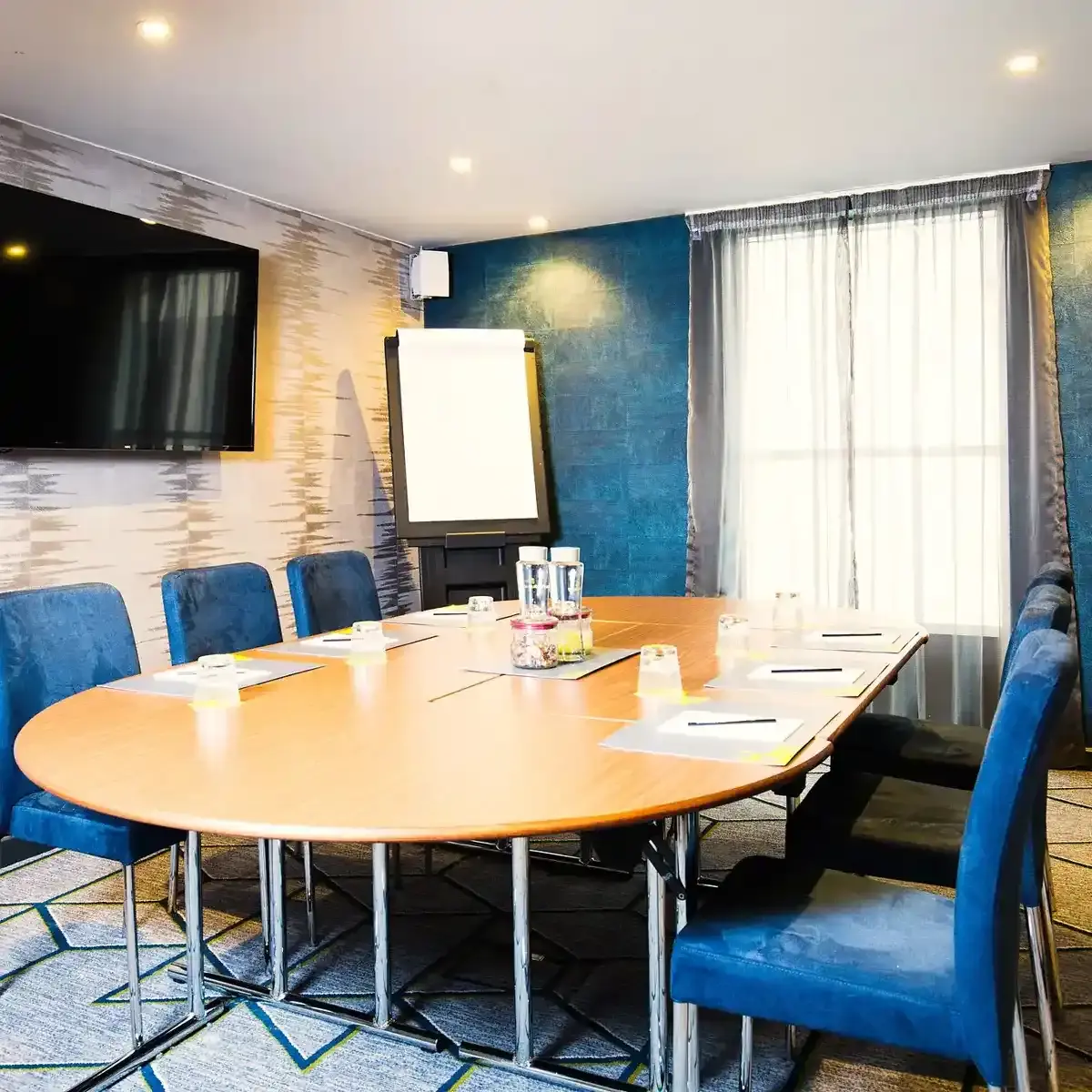 Conference room featuring blue chairs and a flat-screen TV.