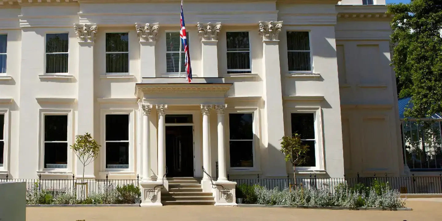 A spacious white building featuring a flag atop.