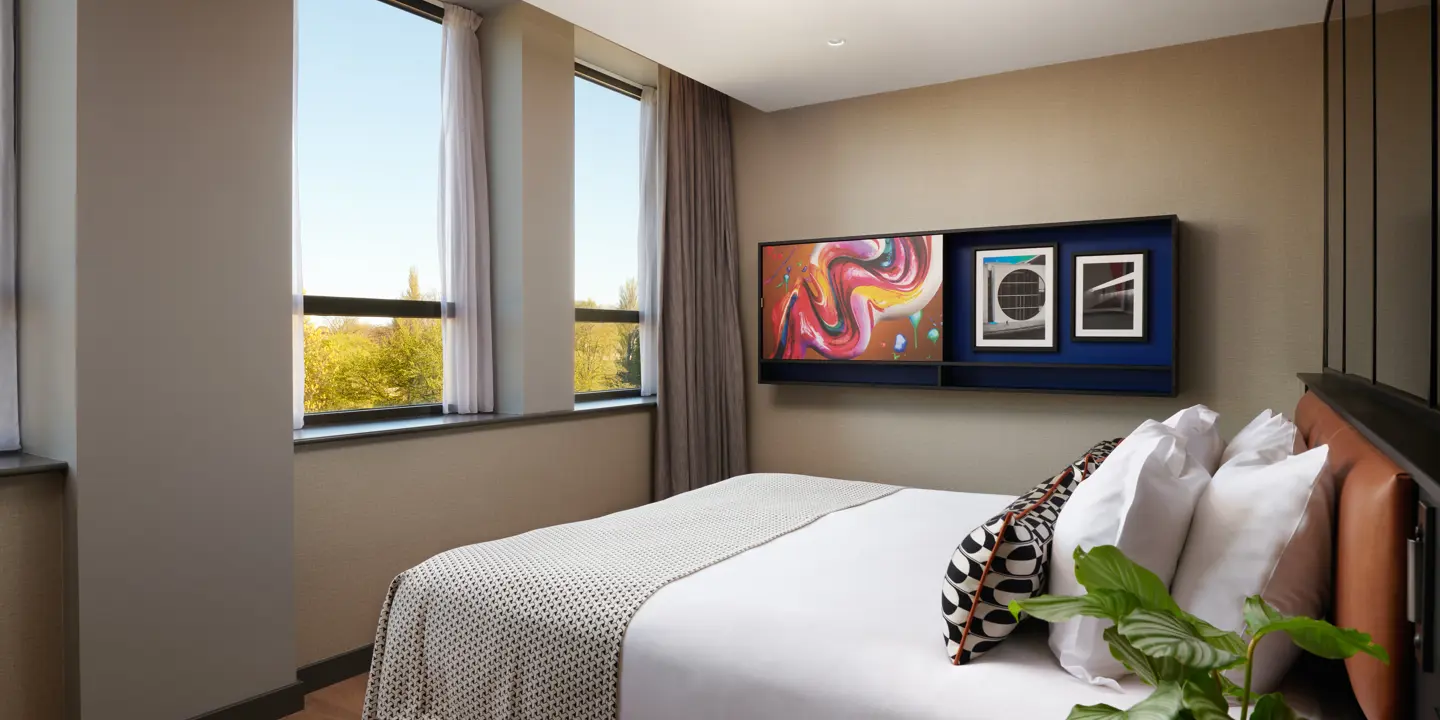 A hotel room featuring a generously-sized bed adorned with an elegant leather headboard.