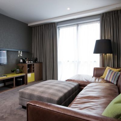 A well-furnished room featuring a flat-screen TV and brown leather sofa.