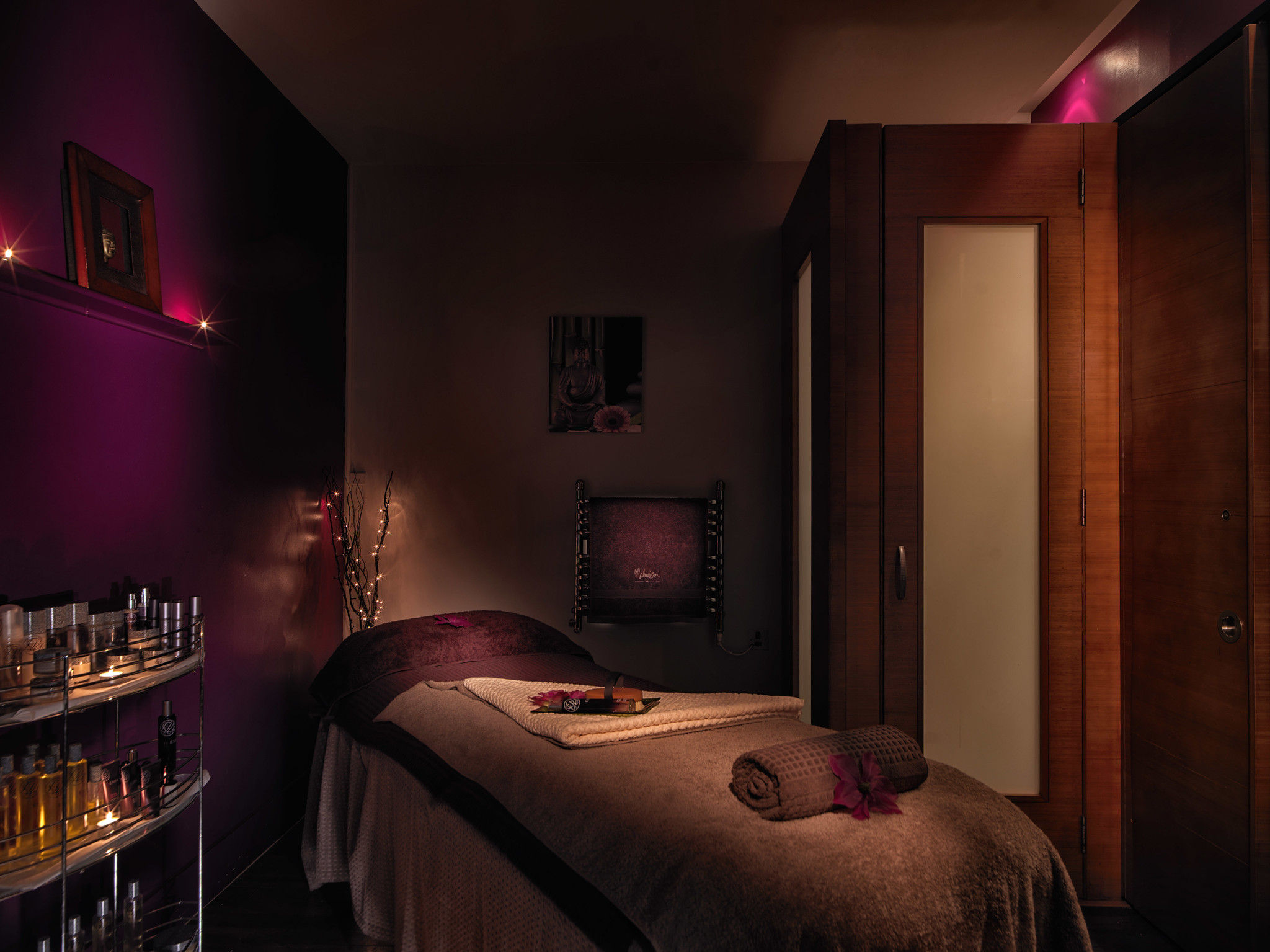 Spa Birmingham set up with massage bed with towels, and shelves neatly stocked with massage oils