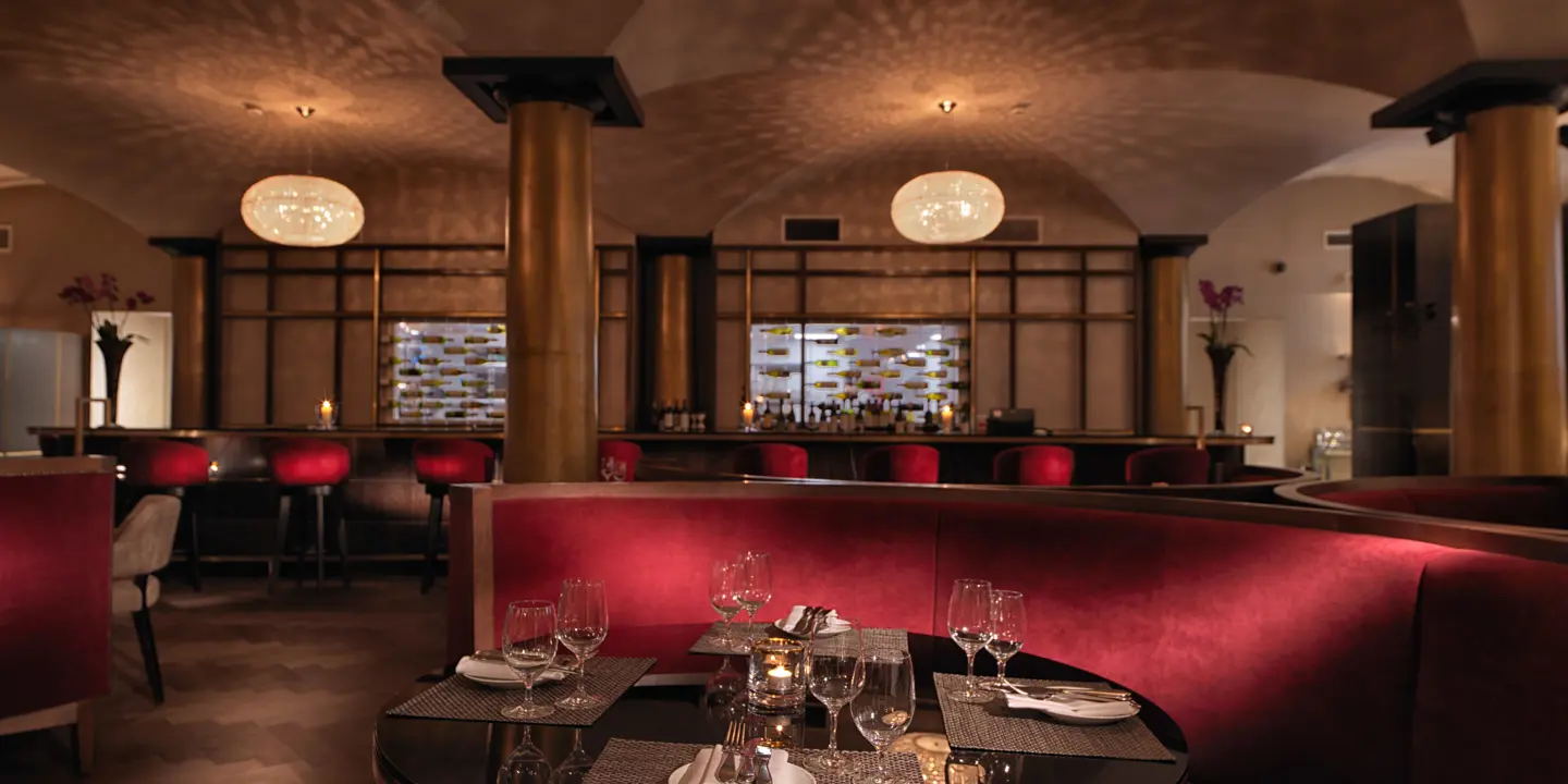 A restaurant featuring red booths, tables, and chairs.