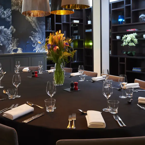 A beautifully arranged dining table with elegantly set place settings and a vase with flowers.