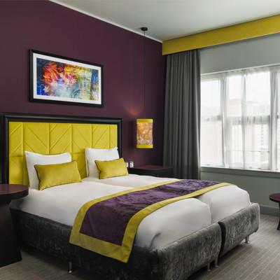 Stylish hotel room featuring two beds, coffee table and a chair.