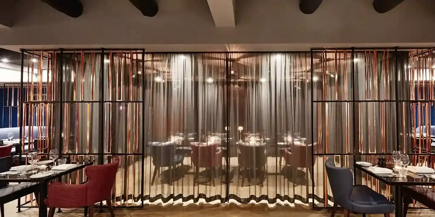 A restaurant featuring a spacious room adorned with black tables and fabric chairs.