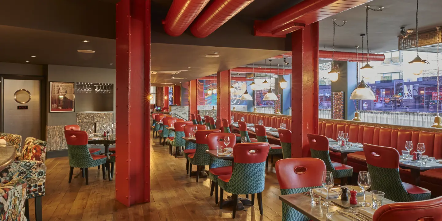 An eatery featuring vibrant red walls and stylish green chairs.