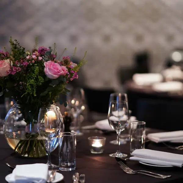 Table set for a formal dinner with a vase of flowers.