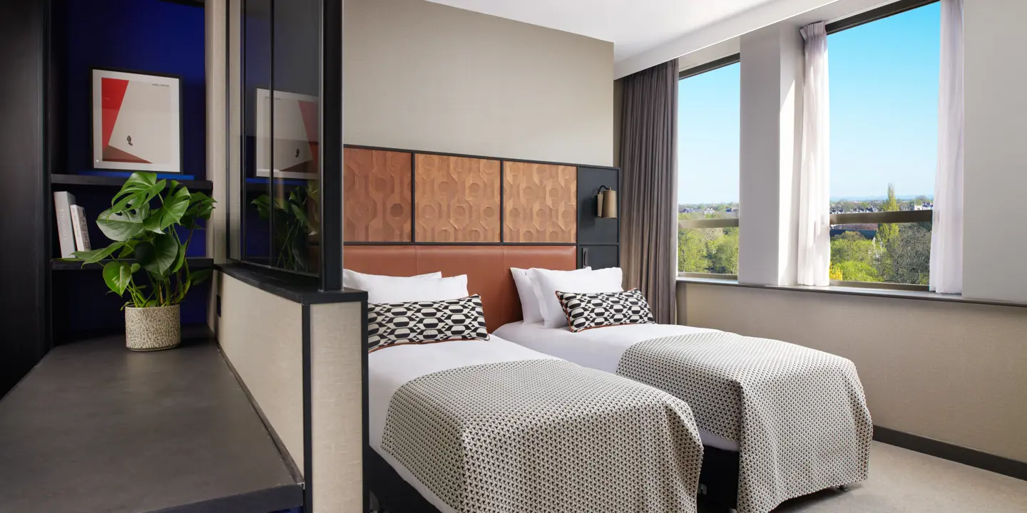 Two beds placed side by side with leather headboards.