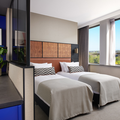 Two beds placed side by side with leather headboards.