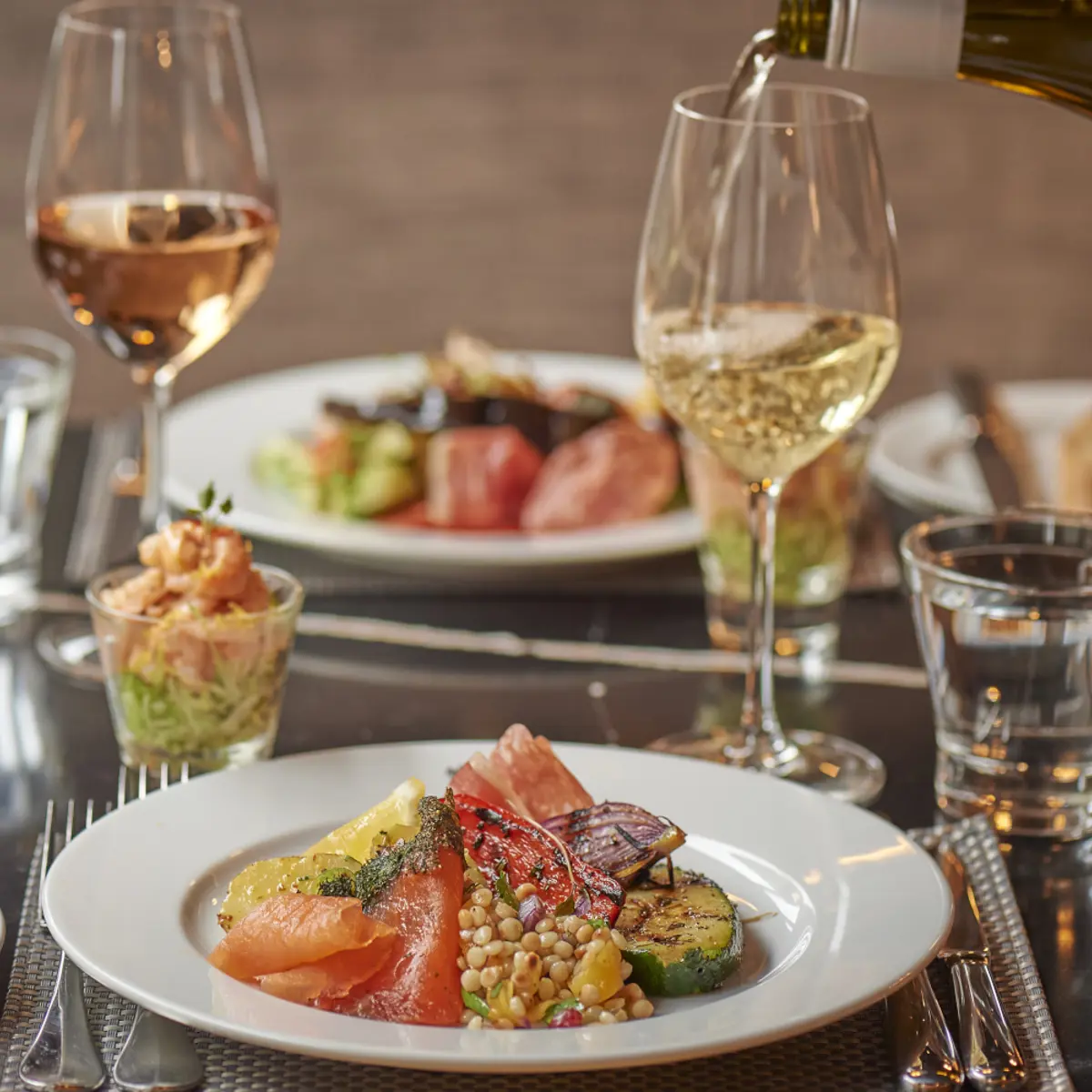 A glass of wine being poured over a plate of food.