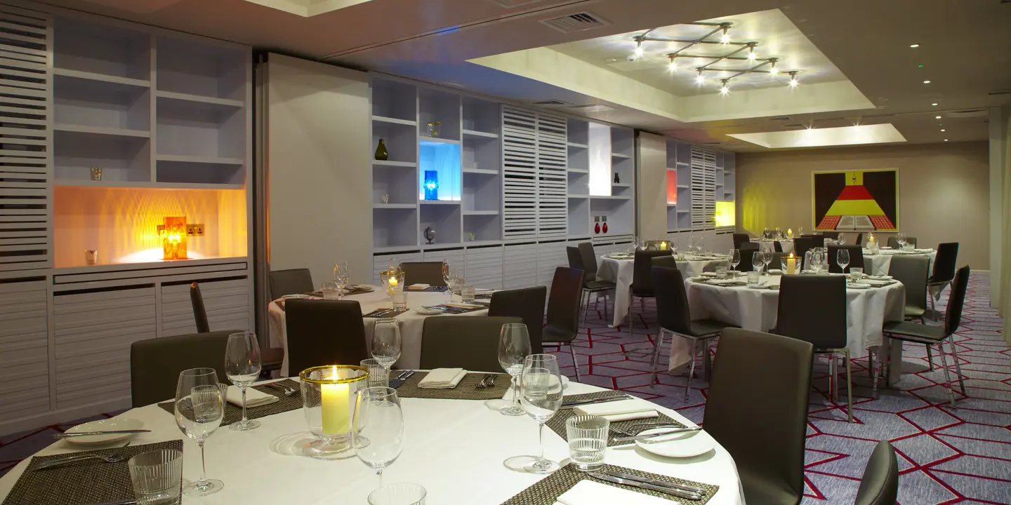 A dining room featuring multiple round tables elegantly decorated with brown chairs.