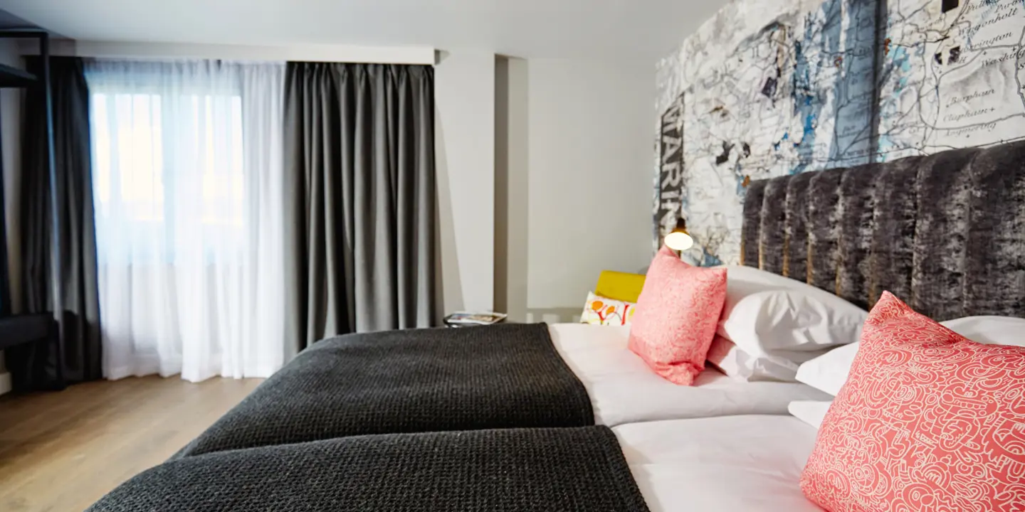 Two beds placed side by side with pink pillows