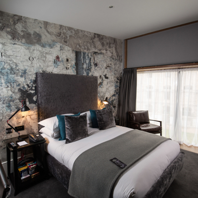 Spacious bedroom featuring a king-sized bed and an elegant chair.