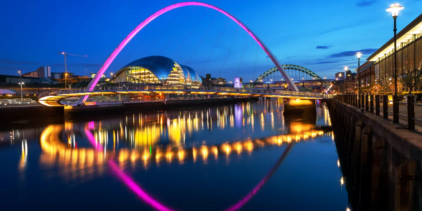 Nighttime view of a bridge spanning over a serene body of water.