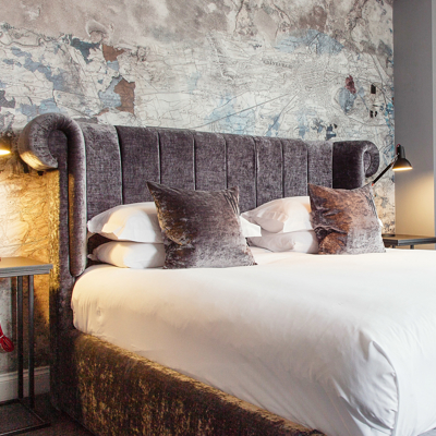 Bed with headboard and pillows in a room.