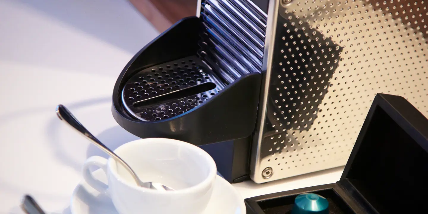 Coffee maker and cup of coffee on a table.