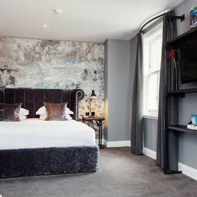 Bedroom featuring a grey velvet bed with black bedside tables.