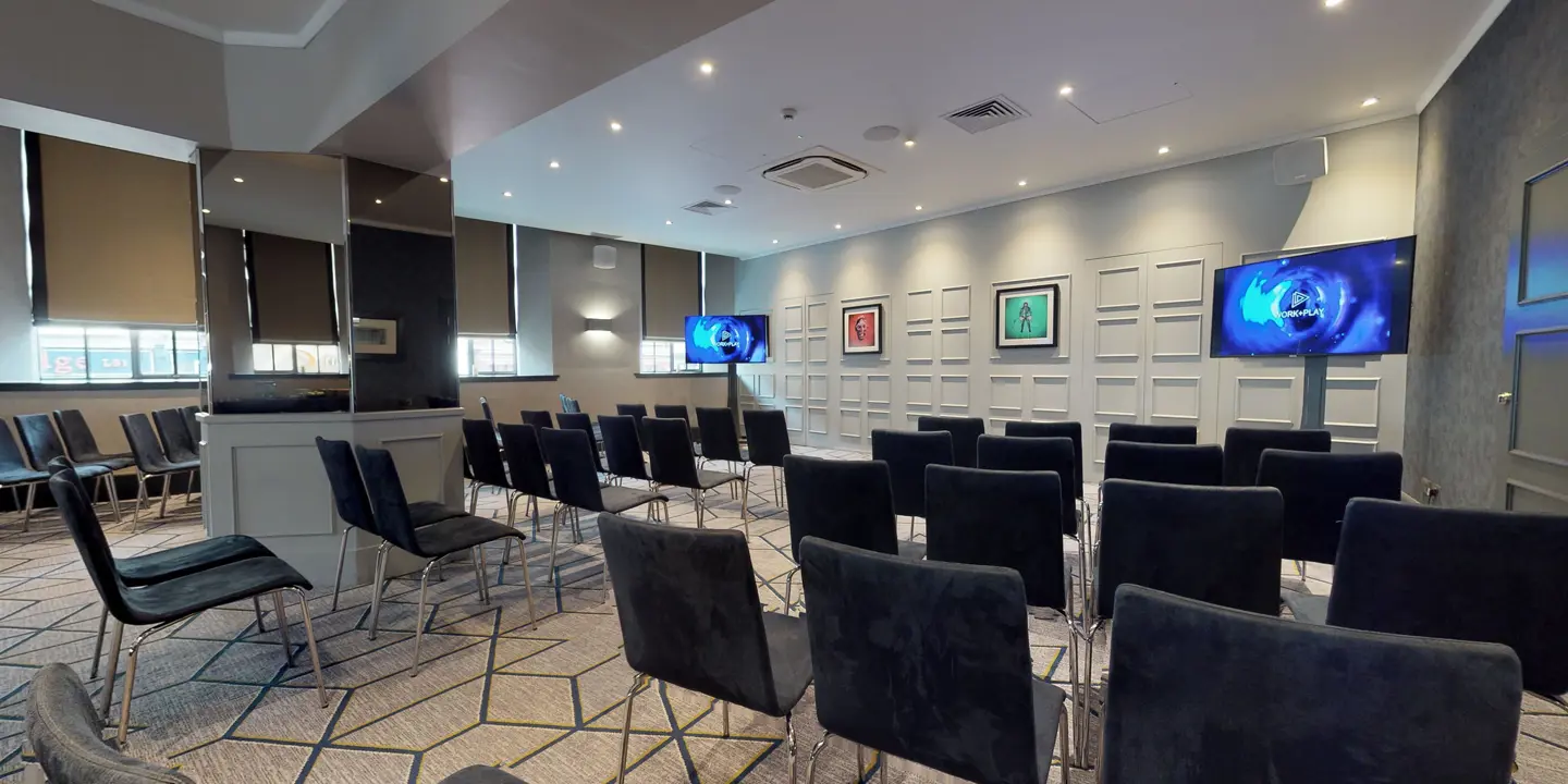 Conference room featuring neatly arranged rows of chairs and sleek flat screen televisions.