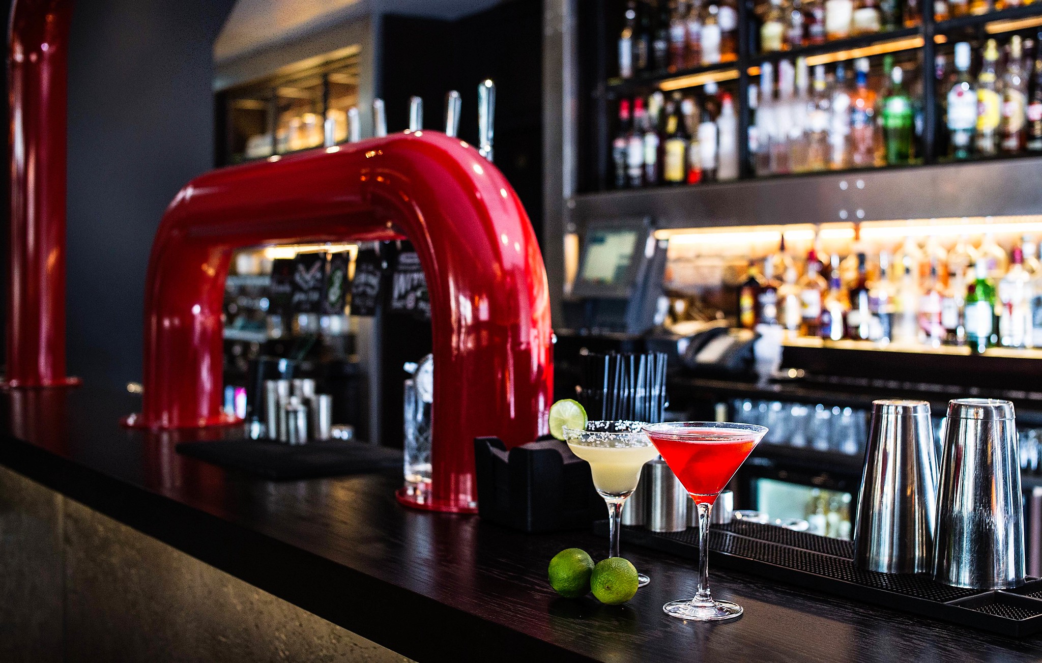 Two cocktail glasses placed on a bar counter with slices of lime.