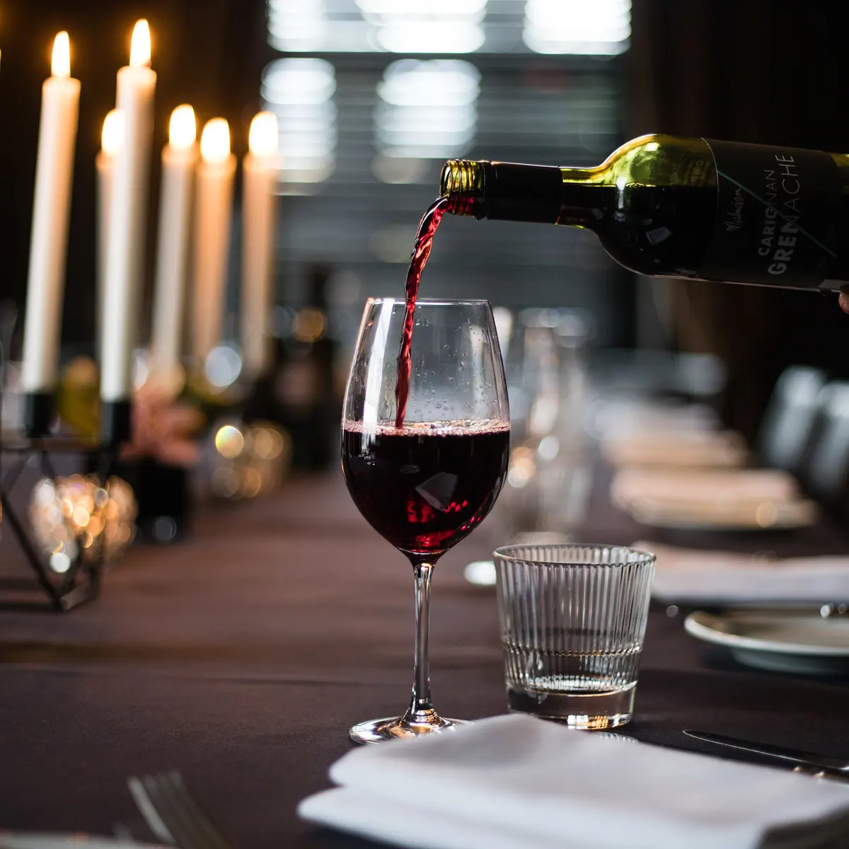 A person pouring wine into a glass.