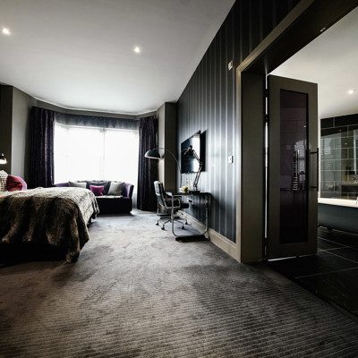 Grey decorated room, with a bed, sofa, desk and tv.