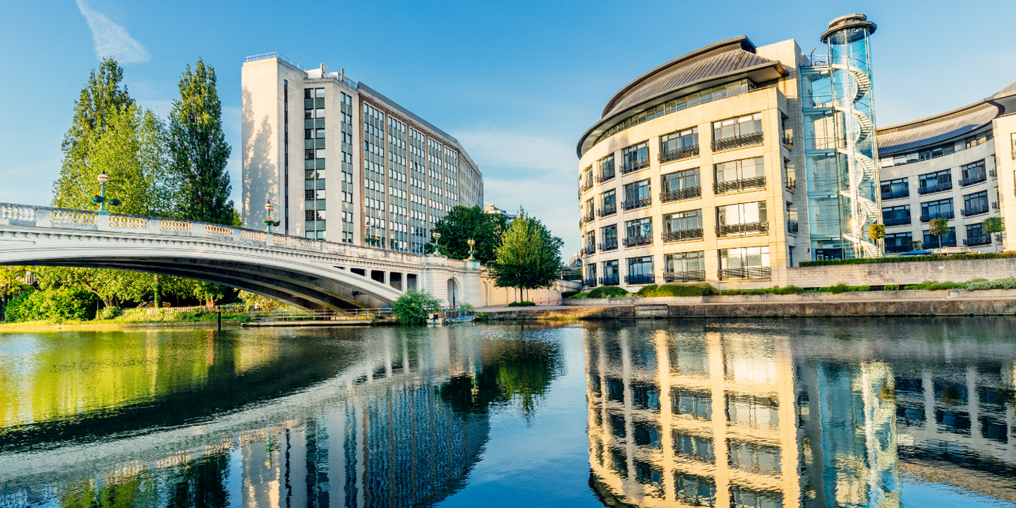 A bridge spanning a body of water alongside towering buildings.