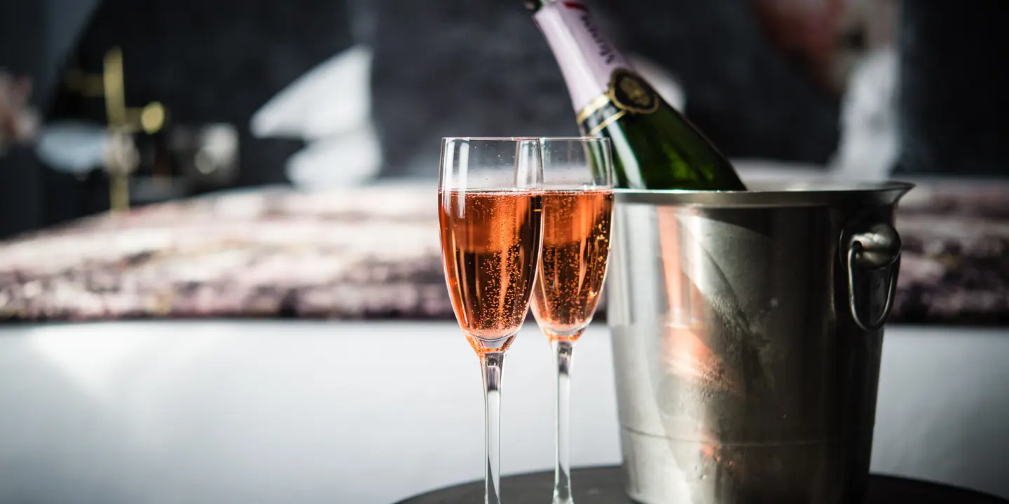 A bottle of champagne and two wine glasses placed on a table.