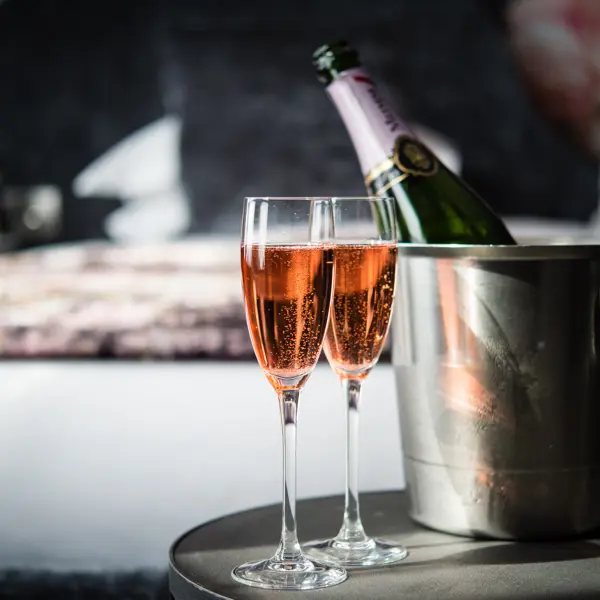 A bottle of champagne and two wine glasses placed on a table.