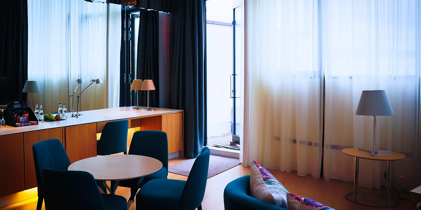 Room filled with a desk, 4 blue chairs around a table and a sofa.