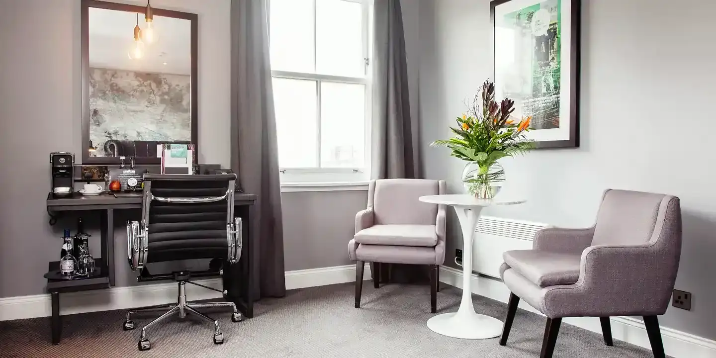 Two chairs, a table and a desk in the corner of a room.